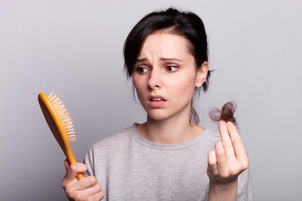 beautiful woman holding comb in her hands and hair loss baldness