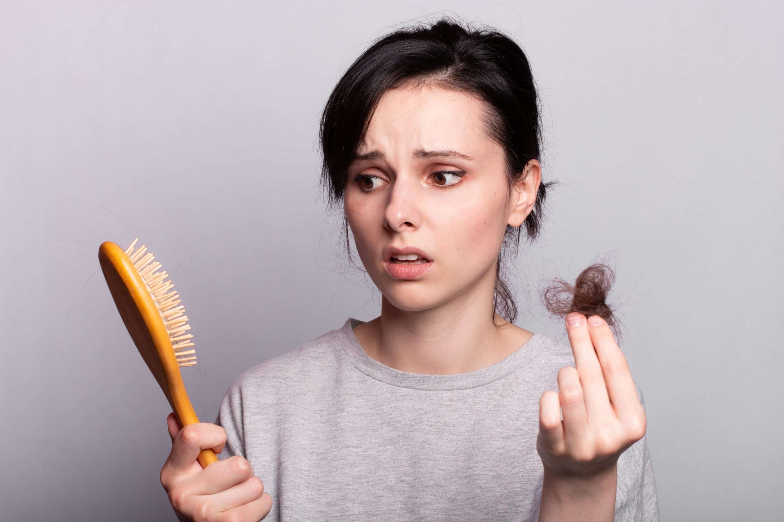 beautiful woman holding comb in her hands and hair loss baldness scaled