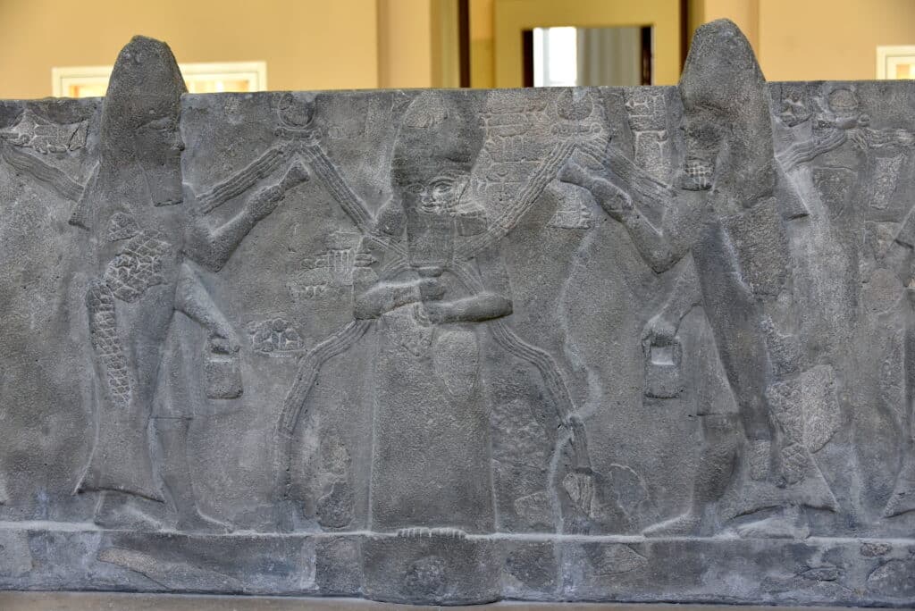 God Ea Sumerian Enki flanked by fish cloaked apkallus part of a basalt water basin from Assur Iraq. Reign of Sennacherib 7th century BCE. Pergamon Museum